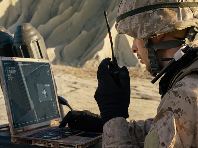 Military personnel talking on radio while on the computer