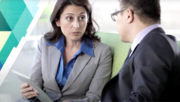 man and woman conversing and looking at tablet