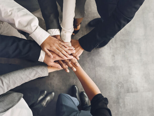 team of people putting their hand in the middle for teamwork